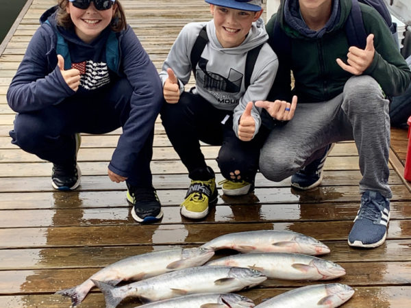 Three kids giving thumbs up over their fishing catches