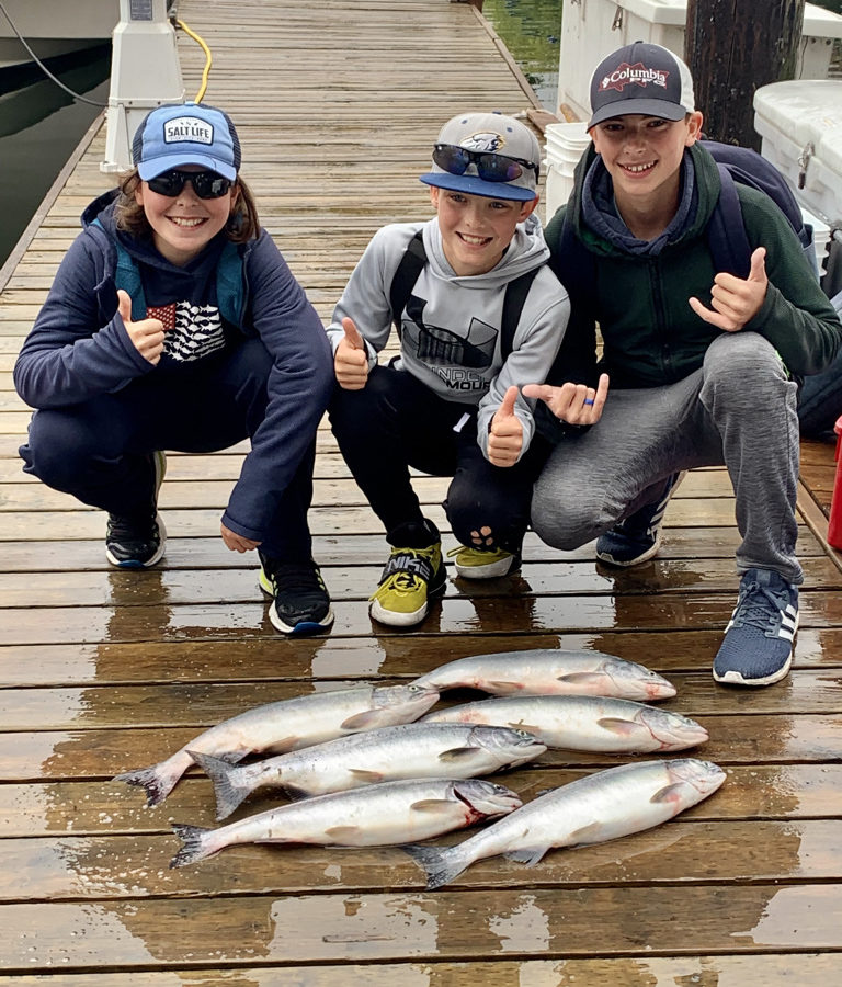 Three kids giving thumbs up over their fishing catches