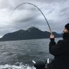Reeling in a hooked salmon in Vancouver BC ocean waters